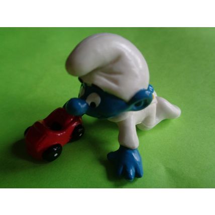 Baby smurf playing with a red toy car