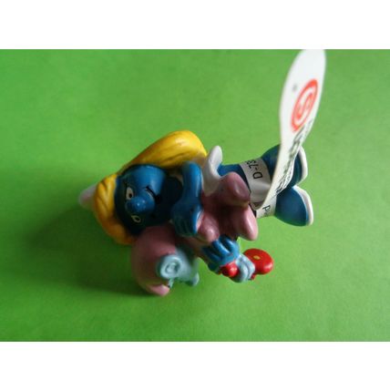 Smurfette smurf holding a pink baby and rattle With a label