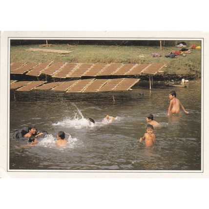 Children bathing next to racks of Tobacco Thailand Postcard used