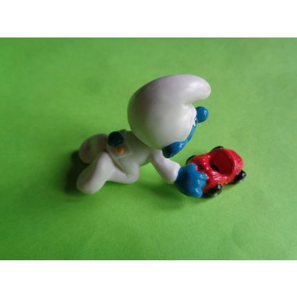 Baby smurf playing with a red toy car
