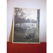 grandmother? & boy sat on a tree trunk. Mast in background photograph =