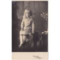 Young Girl Sitting On A Stool And Holding Flowe...