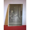 UNKNOWN ELDERLY LADY READING IN A RATTAN CHAIR,...